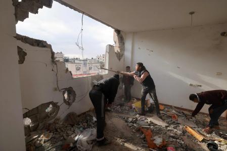 Jóvenes limpian los escombros del interior de un edificio dañado en Rafah
